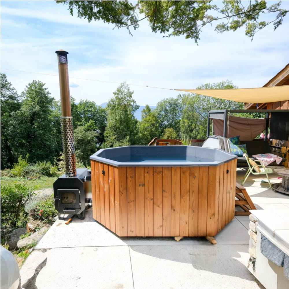 Bain nordique en bois avec poêle externe installé sur une terrasse carrelée près de Grenoble